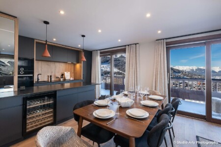 photographie agence immobilière dans les 3 Vallées : salle à manger cuisine ouverte et balcon avec vue montagne enneigée